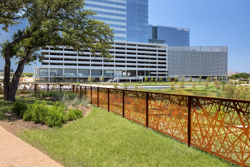 Corten Rusted Metal Railing in Grassy Landscape Area with Cityscape in Background