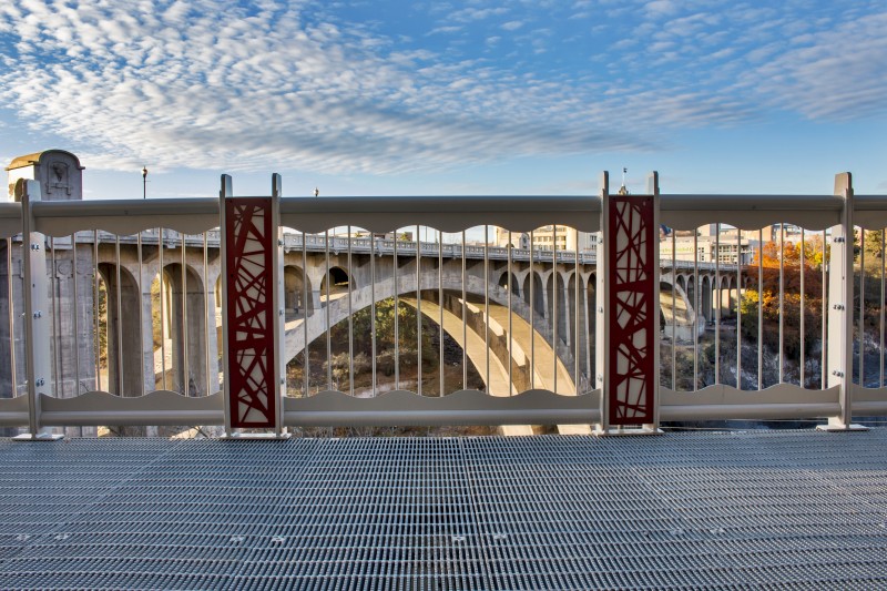 Red Nest Pattern Railing Accent Panels With 20th Century Concrete Bridge in Background